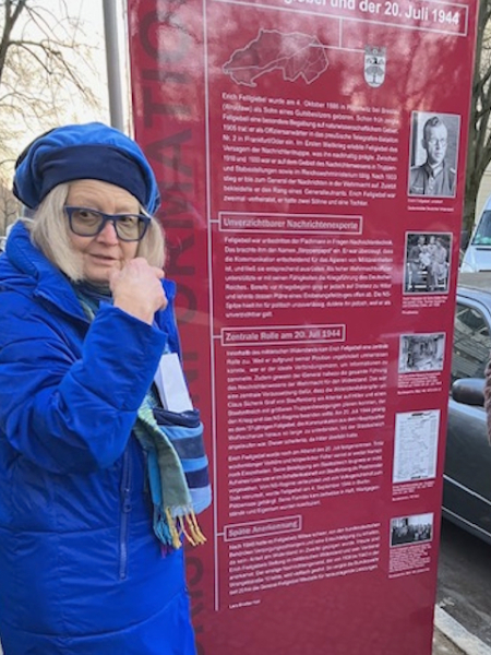 Barbara Fellgiebel neben einer roten regionalhistorischen Informationsstele in Erinnerung an den Widerstand vom 20. Juli und Erich Fellgiebel in Zehlendorf